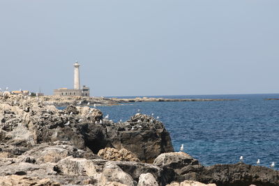 Lighthouse by sea against clear sky