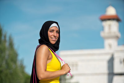 Portrait of smiling young woman standing against sea