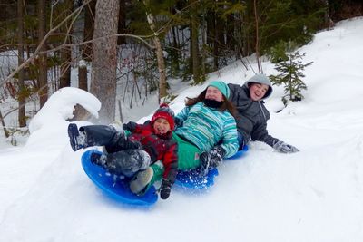 Happy siblings enjoying sledge ride on snow covered field
