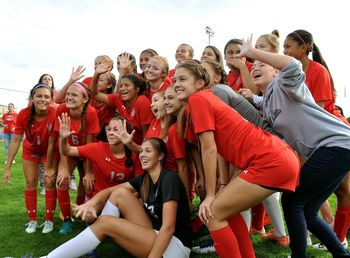 Group of people standing on soccer field against sky