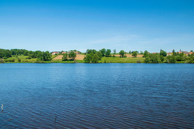 Scenic view of lake against clear blue sky