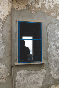 Man looking through window of old building