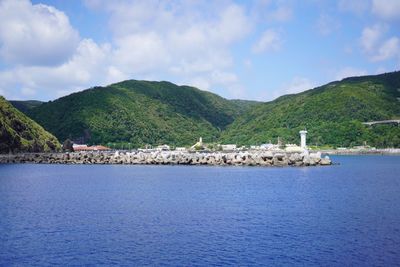 Scenic view of sea by mountains against sky