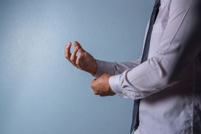 Midsection of businessman holding heart shape against blue sky