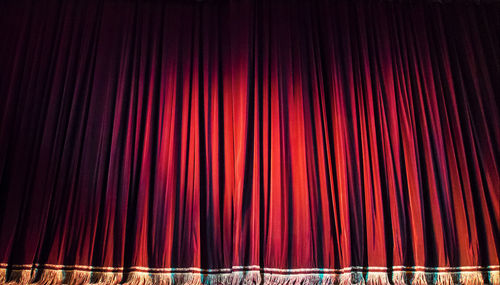 Red closed curtain with spotlight in theater