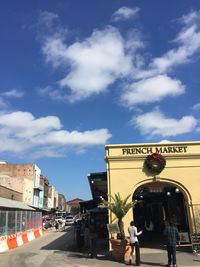 People walking on road against cloudy sky
