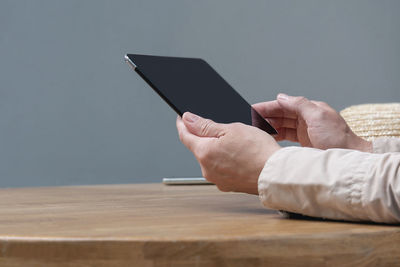 Midsection of man using mobile phone on table