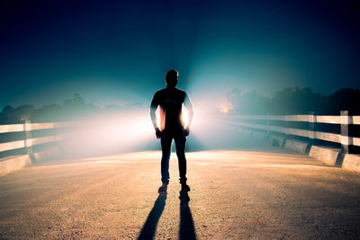 Rear view of man overlooking bridge at night