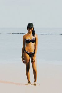 Young woman standing on beach against sky