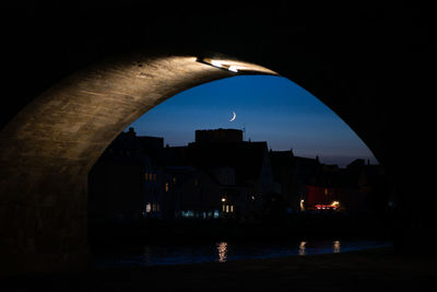 Arch bridge over river in city at night