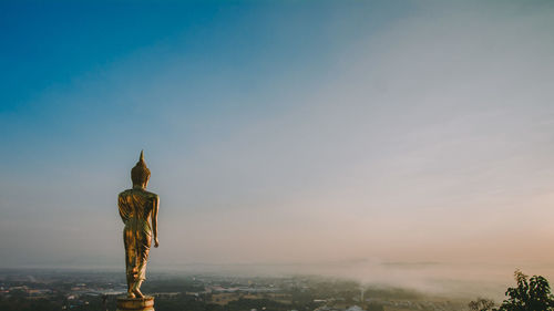 The buddha statue is on the top of a high hill.