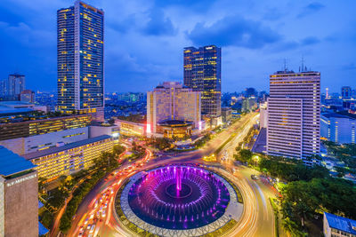 High angle view of illuminated street amidst buildings at night