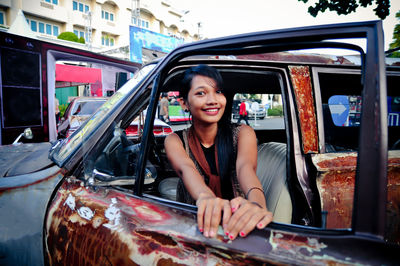 Portrait of smiling young woman standing by car