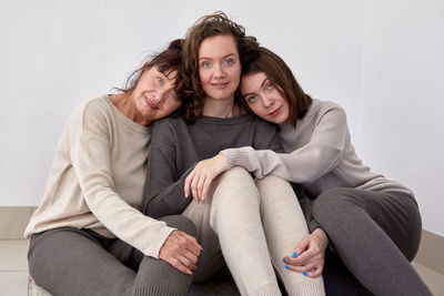 Portrait of females sitting against wall