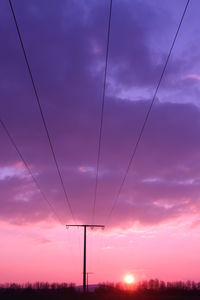 Silhouette telephone pole on field against sky during sunset