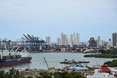 Boats in river by buildings in city against sky