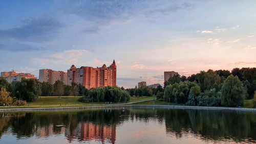 Reflection of buildings in lake against sky at sunset