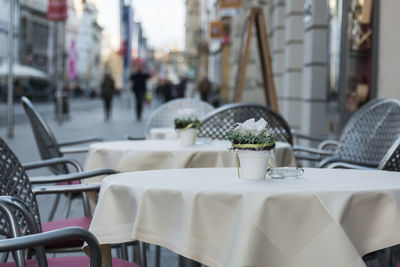 Empty chairs and tables in sidewalk cafe