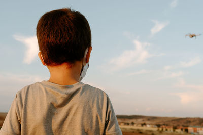 Rear view of boy standing against sky