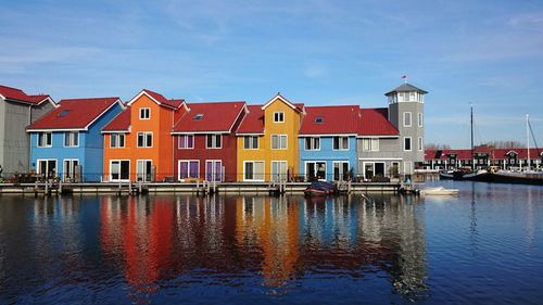 Buildings by canal against sky in city