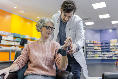 Pharmacist taking blood pressure of customer in pharmacy