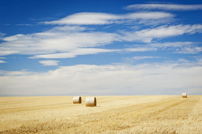 Hay bales on field against sky