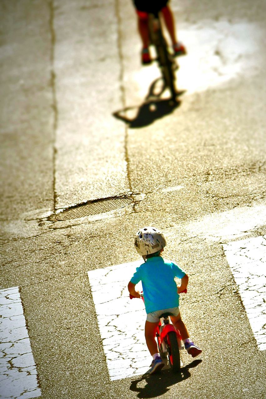 REAR VIEW OF BOY WALKING ON STREET