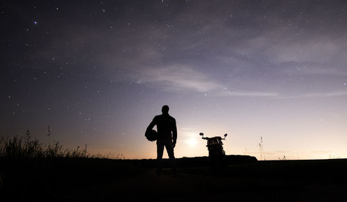 Silhouette man standing on field against sky at night
