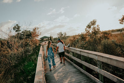 Rear view of people walking on footbridge