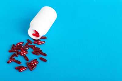 Close-up of pills spilling from bottle against blue background