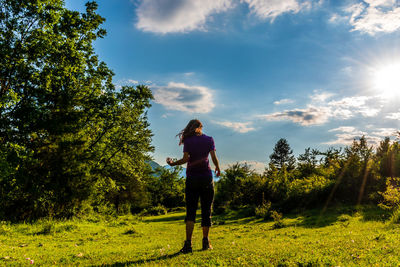 Rear view of man standing on field against sky