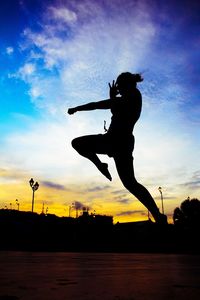 Silhouette of woman jumping at sunset