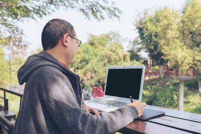 Young man using mobile phone while sitting on table