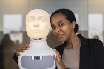 Portrait of young woman with robot voice assistant