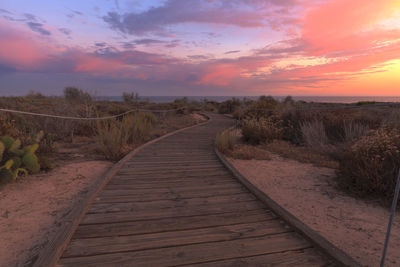 Boardwalk against sky during sunset