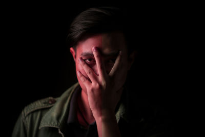 Portrait of young man against black background