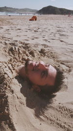 Portrait of man buried in sand at beach