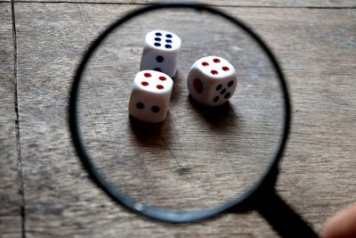 High angle view of dices seen through magnifying glass on wooden table