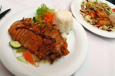 High angle view of peking duck with chop suey and steamed rice served in plate on table
