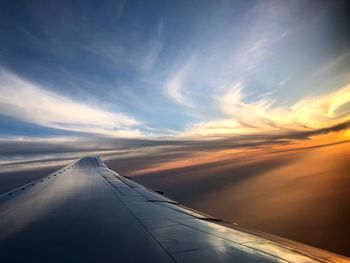 Airplane flying over clouds during sunset