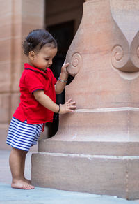 Toddler baby boy cute facial expression standing with wall support in casual appearance at outdoor