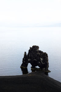 Rocks on sea shore against clear sky