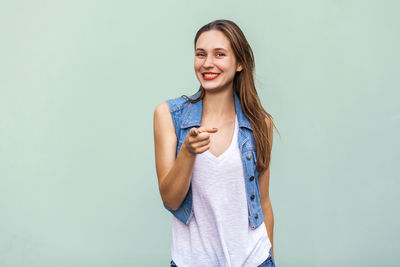 Portrait of smiling young woman against blue background