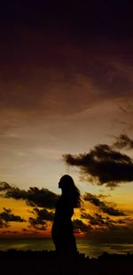 Silhouette woman standing against sky during sunset