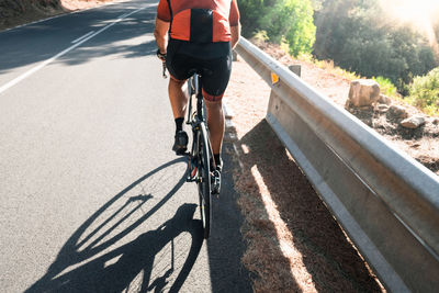 Low section of man riding bicycle on road