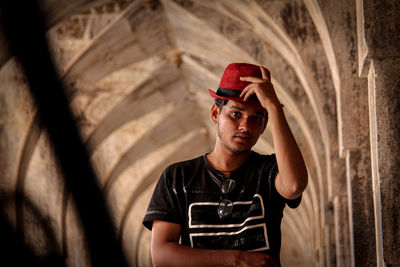 Portrait of young man standing against wall