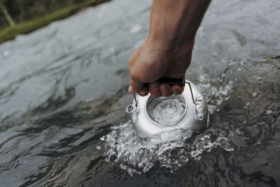 Cropped hand filling water in tea kettle