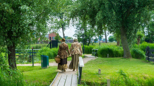 Rear view of woman walking on pathway amidst trees in park