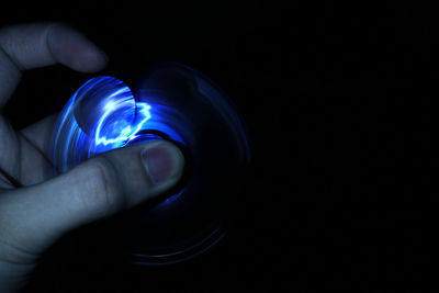 Close-up of hand holding illuminated light against black background