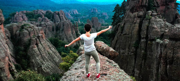 Rear view of woman standing on mountain against sky